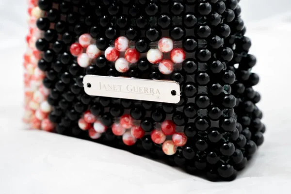 BOLSA MINI DE PERLA NEGRA CON LATERAL DERECHO BLANCA MANCHADA ROJO CON  6 FLORES AL FRENTE