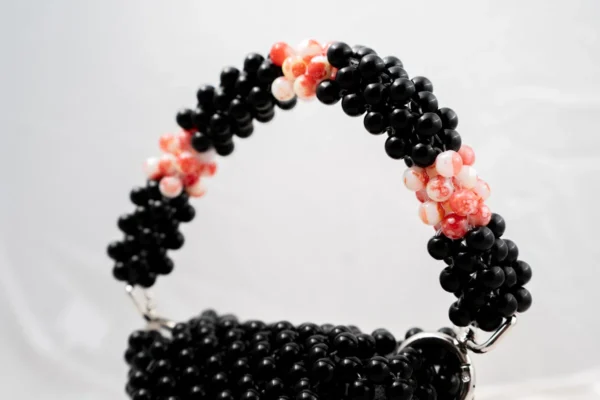 BOLSA MINI DE PERLA NEGRA CON LATERAL DERECHO BLANCA MANCHADA ROJO CON  6 FLORES AL FRENTE